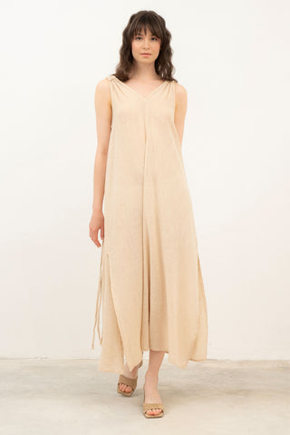 Woman wearing a beige sleeveless dress against a white background